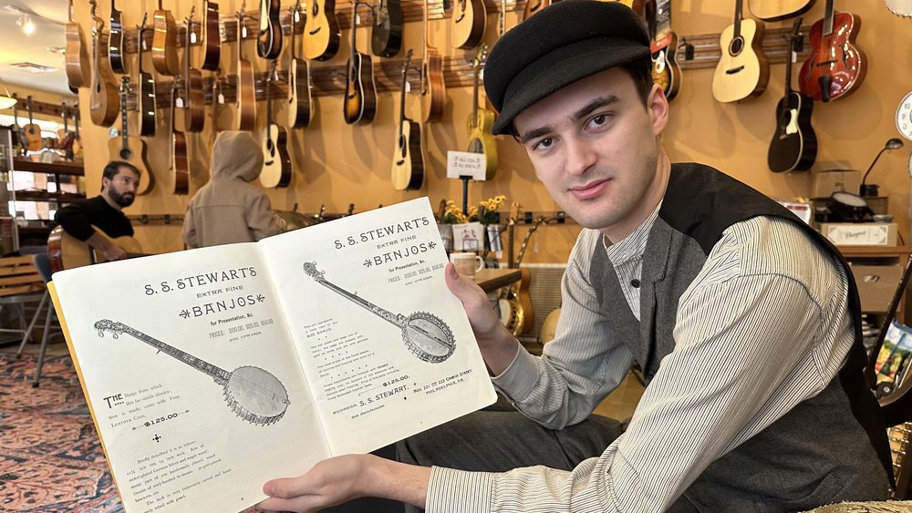 Gavin Rice displays an 1890s Stewart catalog featuring the grand Presentation banjos.