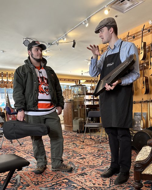 Gavin Rice explains the complexities of an 1897 zither to an RIT student who is mesmerized or par...