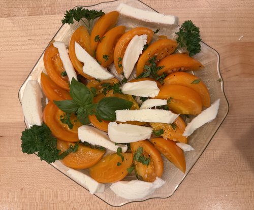 A yellow tomato salad with fresh mozzarella cheese, served with a crusty ciabatta, roasted garlic...