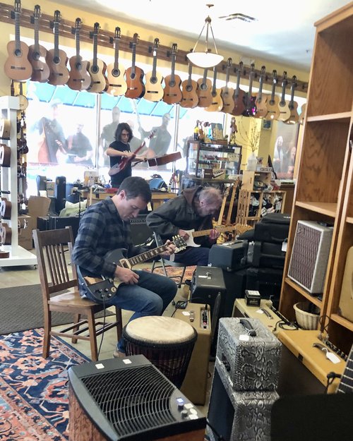 Customers enthusiastically try out instruments while Overhand Sam Snyder juggles guitars in the b...